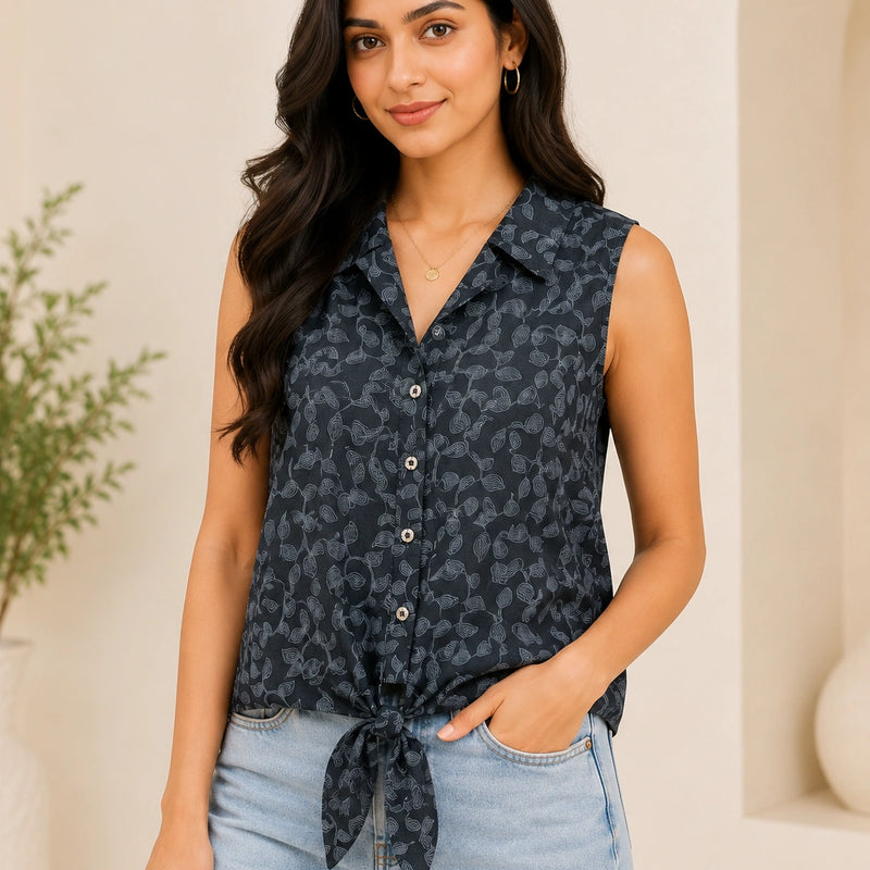Woman wearing a sleeveless patterned top and light blue jeans against a neutral background