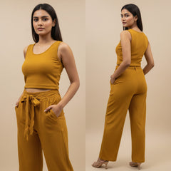 Woman wearing a mustard yellow outfit with a top and pants on a beige background