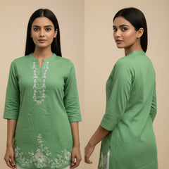 Woman wearing a green kurta with white embroidery on a beige background
