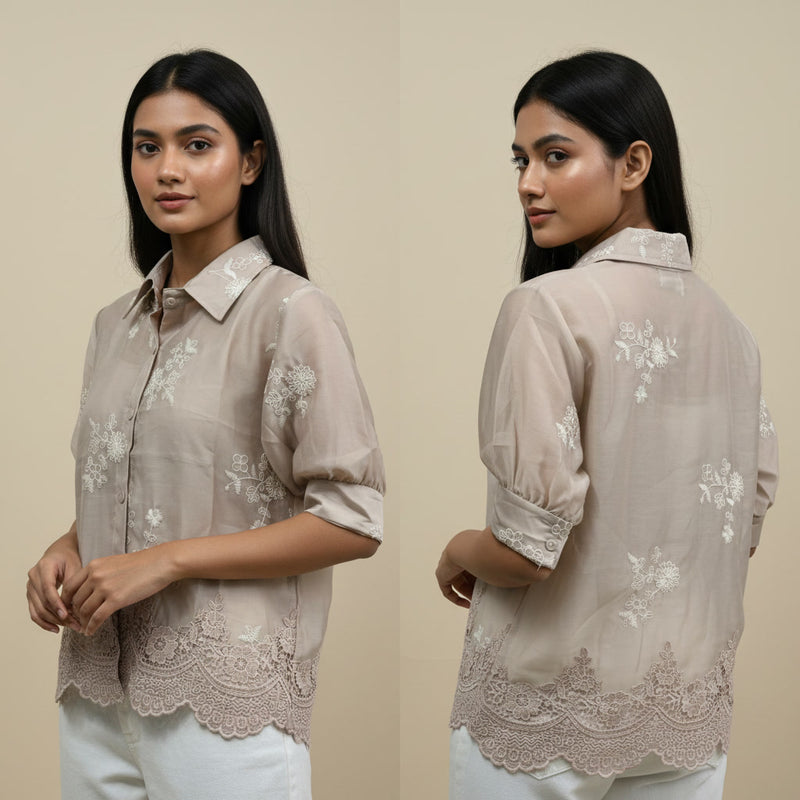 Woman wearing a beige floral embroidered shirt against a beige background