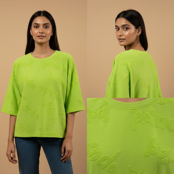 Woman wearing a bright green oversized t-shirt with text design, shown from front and back on a beige background.