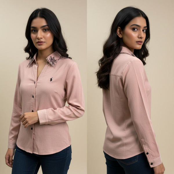 Woman wearing a pink shirt with a floral collar detail, standing against a beige background.