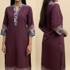 Woman wearing a maroon kurta with floral patterns on a beige background