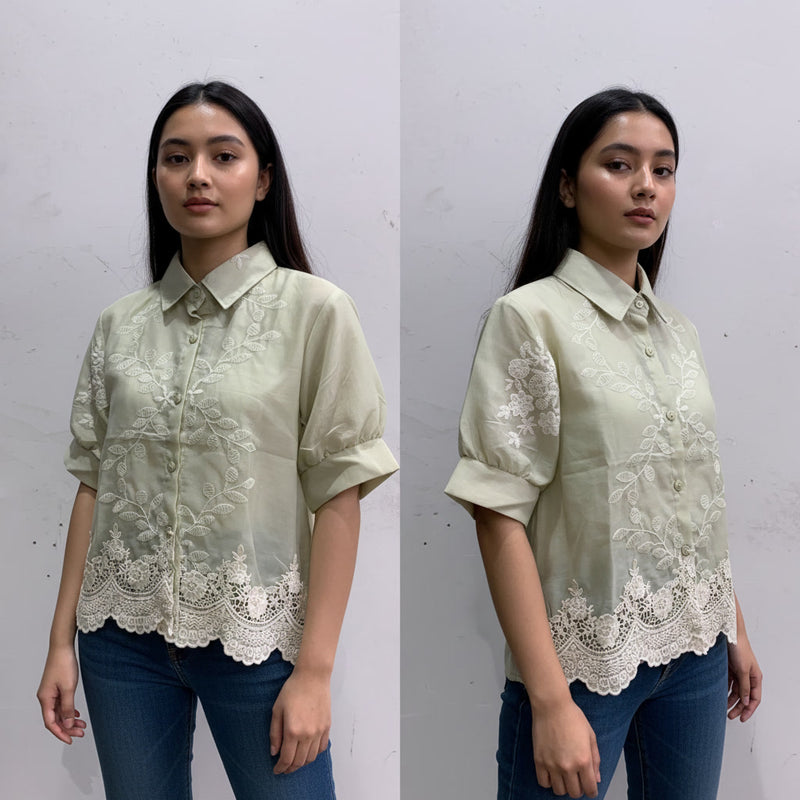 Woman wearing a light green blouse with lace details on a white background