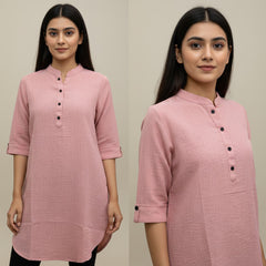 Woman wearing a pink kurta with black buttons on a plain background