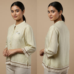 Woman wearing a cream-colored traditional outfit with intricate patterns on a beige background