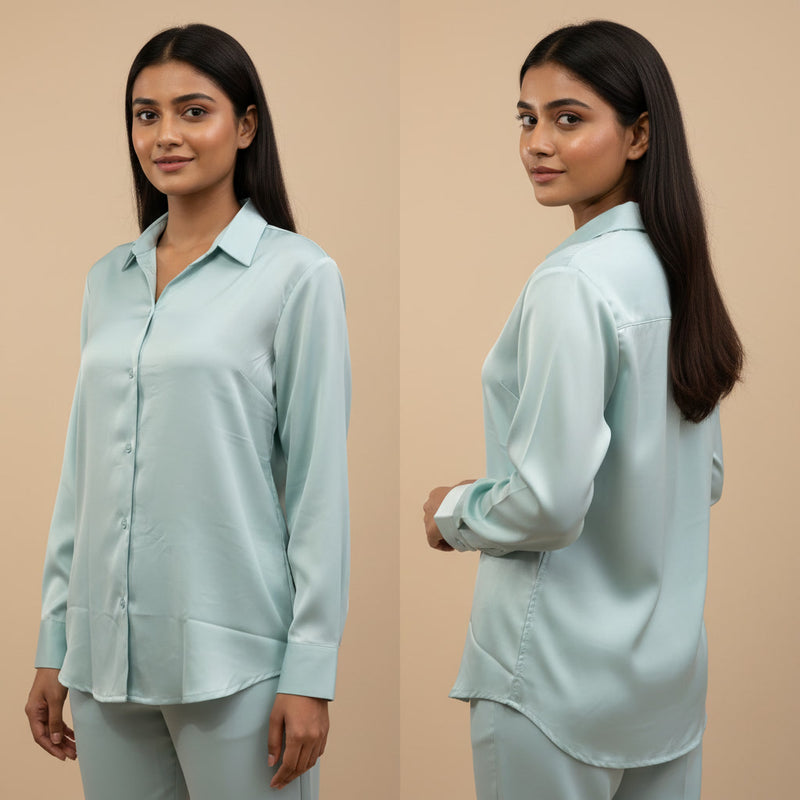 Woman wearing a light blue shirt and pants set, standing against a beige background.