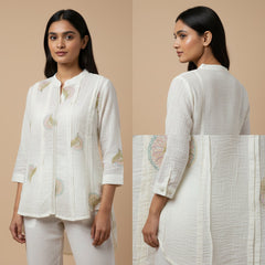 Woman wearing a white embroidered outfit on a beige background