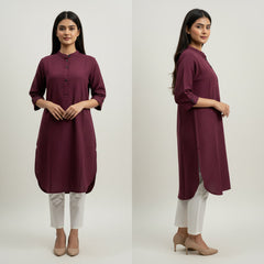Woman wearing a maroon kurta with white pants on a plain background