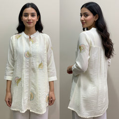 Woman wearing a white embroidered kurta against a plain background