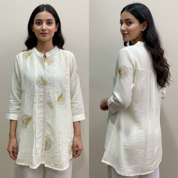 Woman wearing a white embroidered kurta against a plain background