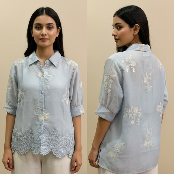 Woman wearing a light blue embroidered shirt, front and back views, on a beige background