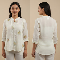 Woman wearing a white embroidered blouse with beige background