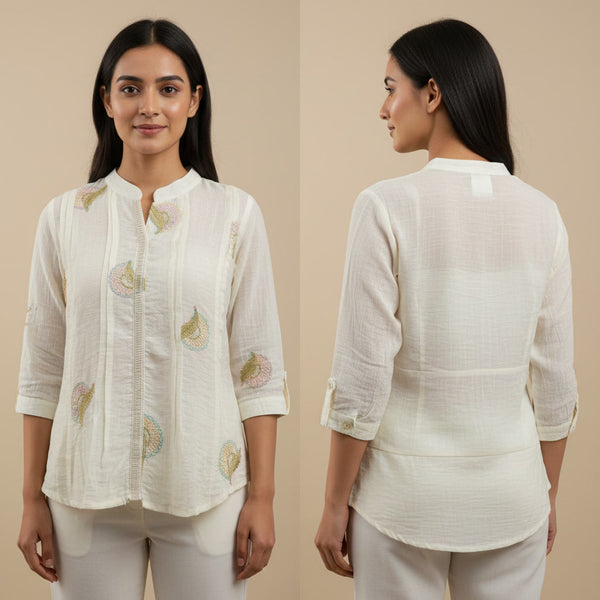 Woman wearing a white embroidered blouse with beige background
