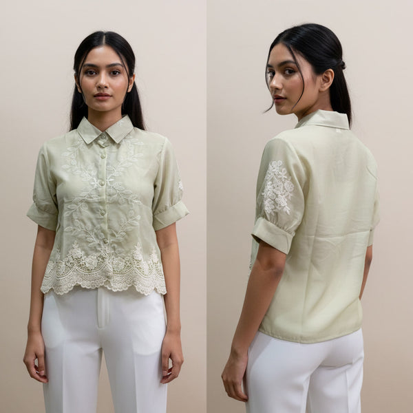 Woman wearing a light green blouse with lace details on a beige background