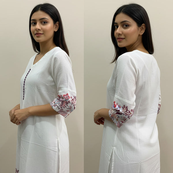 Woman wearing a white outfit with floral sleeves against a beige background