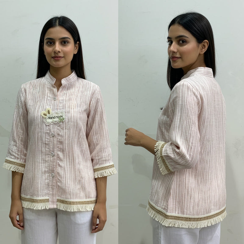 Woman wearing a light-colored striped shirt with a brand logo, standing against a plain background.
