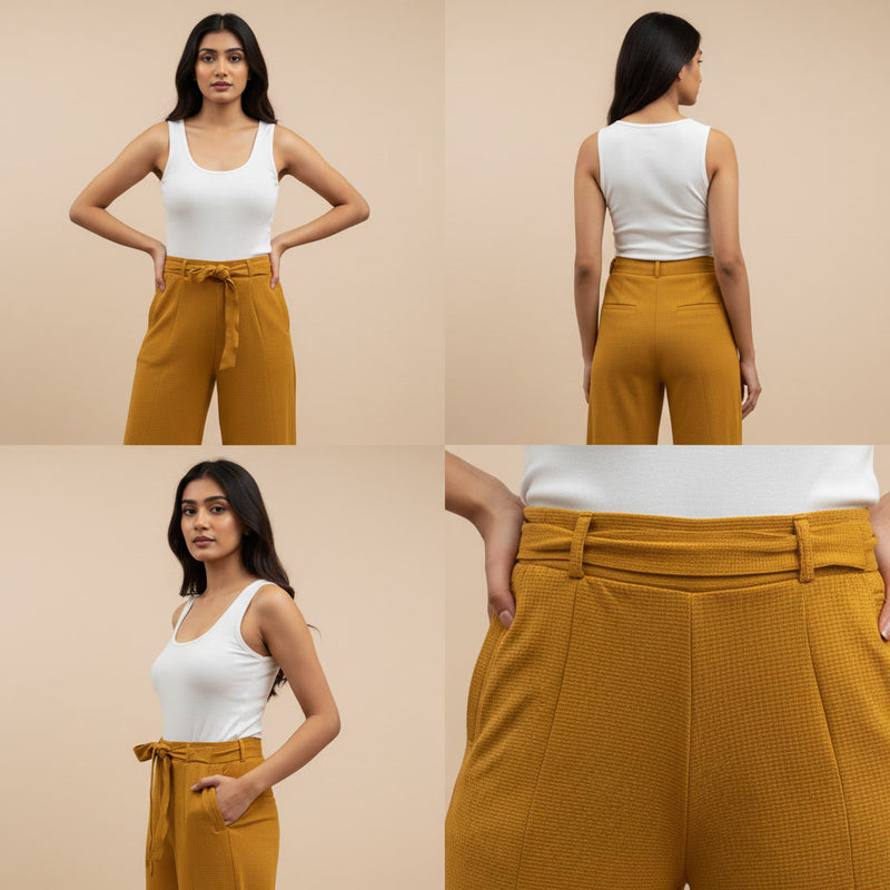 Woman wearing mustard yellow pants with a white top on a beige background