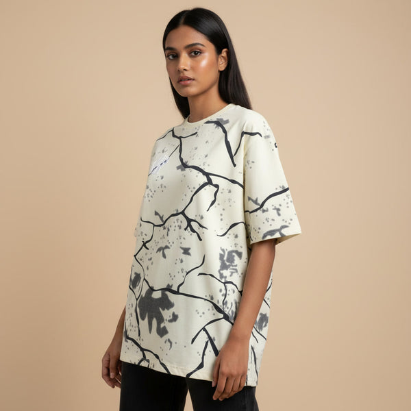 Woman wearing a cream-colored t-shirt with black abstract pattern on a beige background