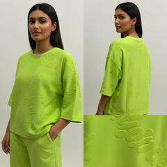 Woman wearing a bright green outfit with detailed fabric texture shown below.