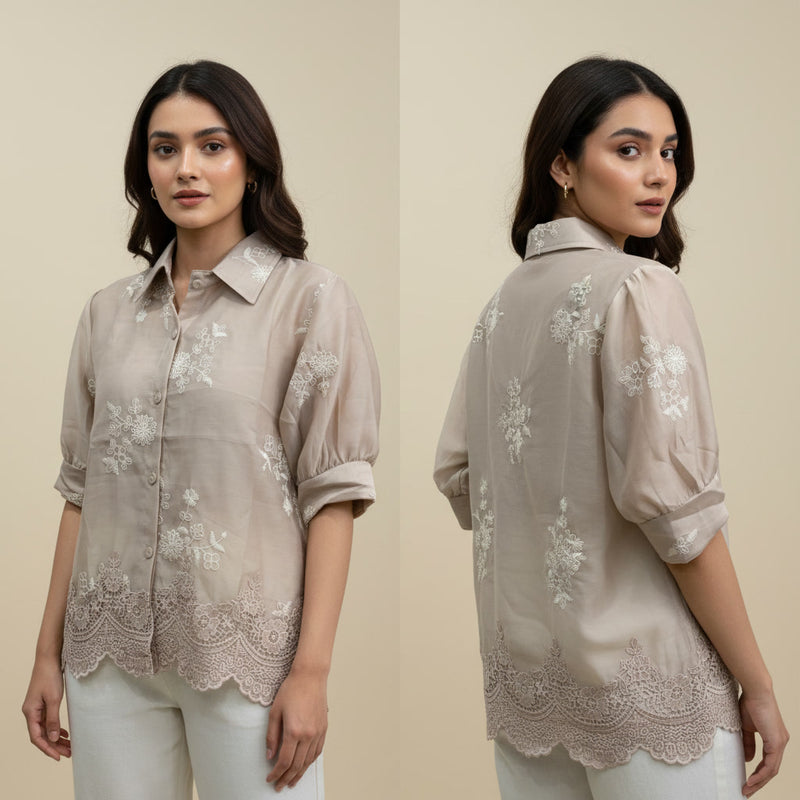 Woman wearing a beige embroidered shirt with a plain background